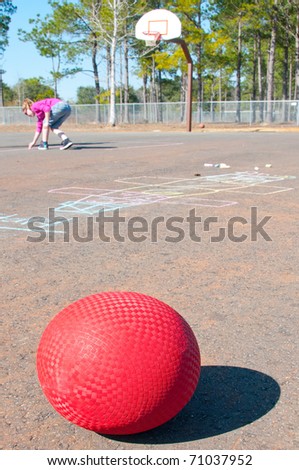 ball on playground with giirl writing chalk