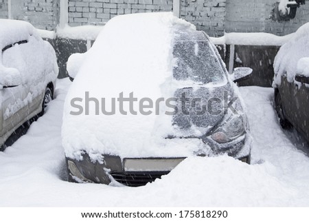 Snow-covered car in the parking lot. Urban scene. After a snowstorm. Clean automobile from the snow.