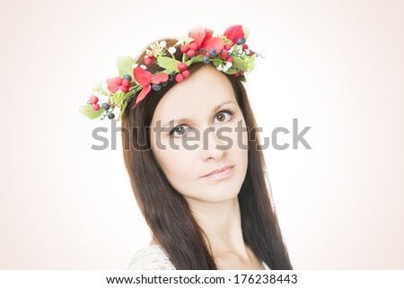 Studio portrait of a young beautiful woman with flower wreath on head. Make-up and hairstyle with flowers.