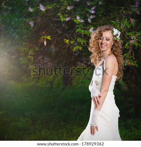 Beautiful bride in a white dress on a lilac background in spring. Professional make-up and hairstyle.