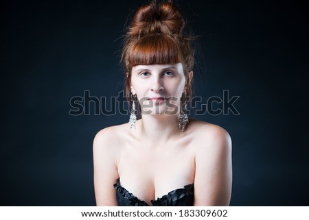 Portrait of a young woman in studio on a gray background. Stylish hairstyle. No makeup, natural skin color.