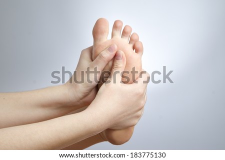 Pain in the foot. Massage of female feet. Pedicures. Studio shot on a gray background.
