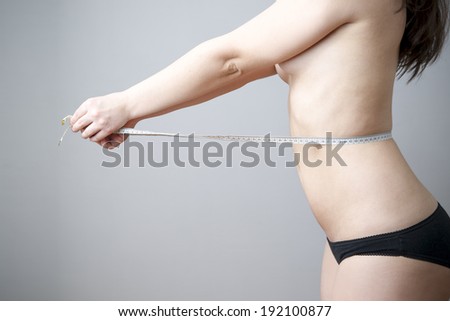 Female body with measuring tape on gray background. Weight loss, diet