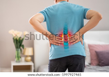 Lumbar spine hernia, man with back pain at home, compression injury of the intervertebral disc in the lower back, photo with highlighted skeleton