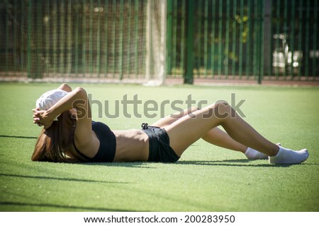 Young woman is engaged in fitness on the green grass. Sports outdoors. Exercise in nature in summer