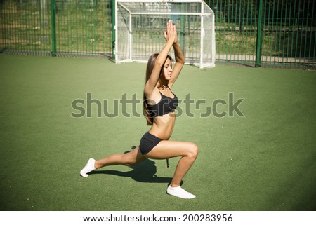 Young woman is engaged in fitness on the green grass. Sports outdoors. Exercise in nature in summer