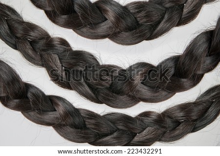 Hair braided in a braid on a gray background. Hairstyle closeup.