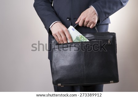 Businessman with a briefcase full of money in the hands of on gray background