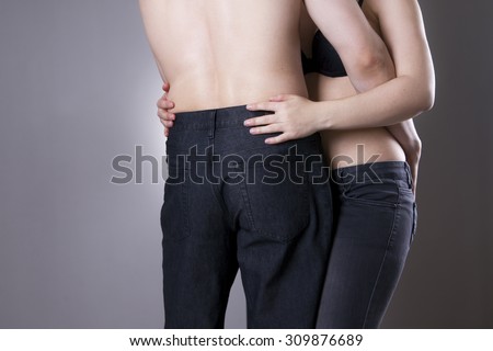 Man and woman in jeans hug each other on a gray background