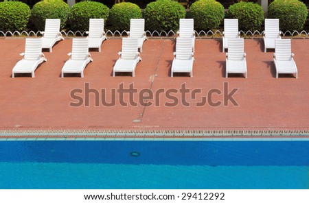 Chaise longues by swimming-pool in a garden