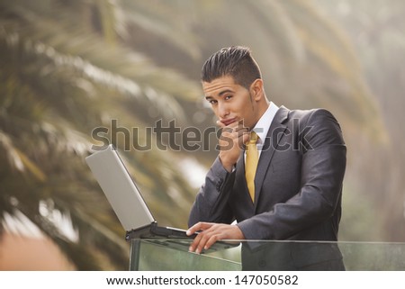 Confident young businessman working with his laptop at the office balcony