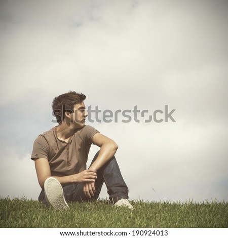 Young men sited on the grass looking away