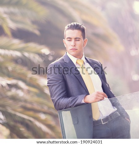Confident young businessman at his office balcony (with backlight)
