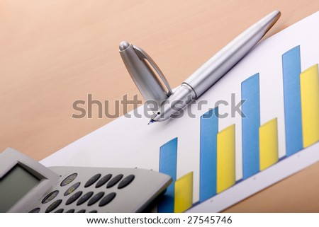 detail of a pen, calculator and some business charts (selective focus)