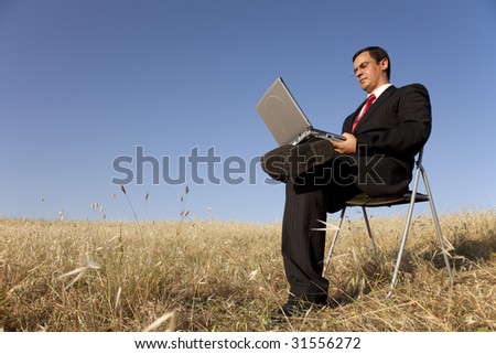 businessman working with his laptop outside in the field