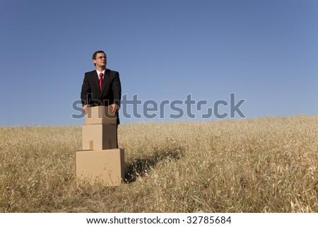 businessman with a stack of boxes at the field