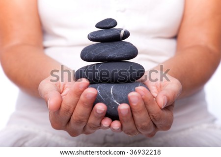 hands holding a stack of black stones (selective focus)