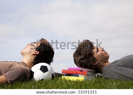two young students sleeping at the grass over books and a soccer ball