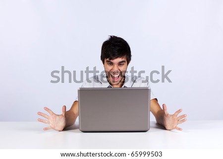 Young man looking to something terrible and screaming to his laptop