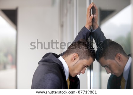 frustrated businessman banging his head at the office window