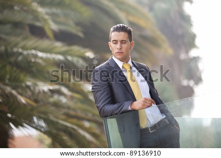 Confident young businessman at his office balcony (with back light)