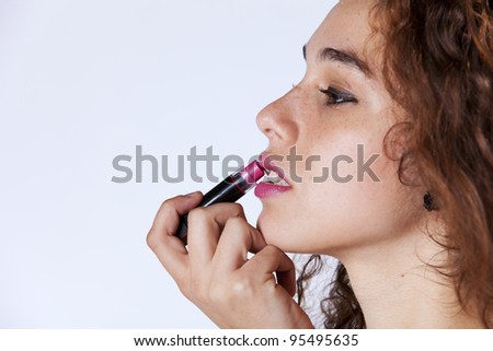 Sensual young woman applying lipstick (isolated on gray)