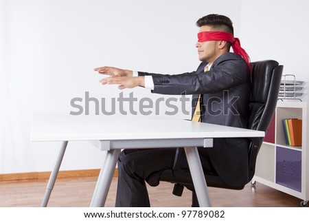 Businessman at his office with scarf covering his eyes