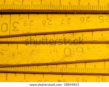 Old yellow wooden zigzag rule closeup background.