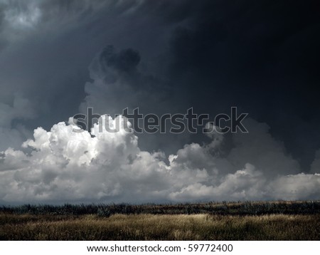 Autumnal field under dark thunderstorm sky.