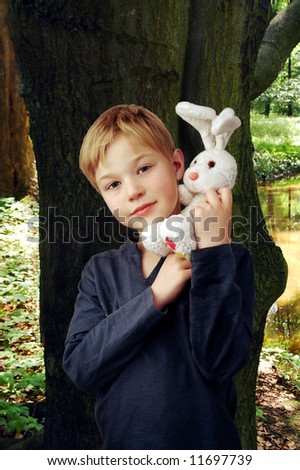 Cute boy with white bunny in park