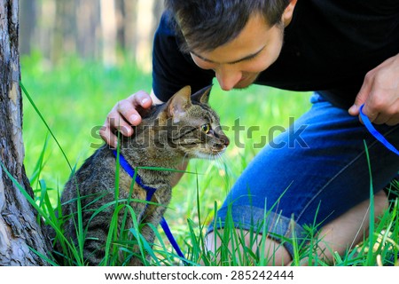 cat on a leash outdoor with male owner