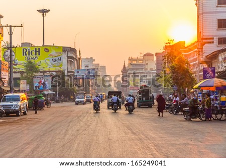 MANDALAY - FEBRUARY 26: People, cars and bikes on the streets in the center of the city at sunset on February 26, 2013 in Mandalay, Myanmar.