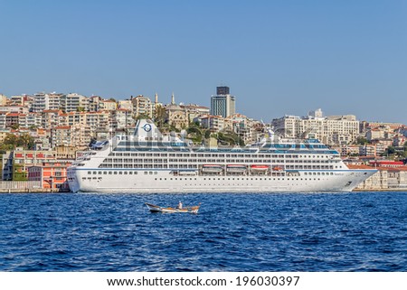 ISTANBUL, TURKEY - SEPTEMBER 29, 2013: Big cruise ship Nautica anchored in the Beyoglu district and small fishing boat passing in the front.