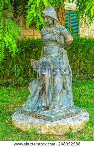 SUPETAR, CROATIA - September 16, 2014 Bronze statue of a girl in a green yard, work of Croatian sculptor Ivan Rendic.