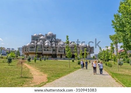 PRISTINA, KOSOVO - JULY 01, 2015: People walking in the park by the famous building of the National library of Kosovo designed by architect Andrija Mutnjakovic.