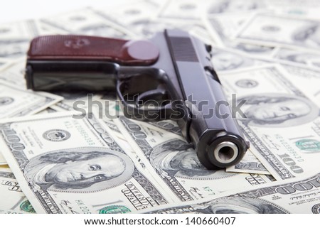 Money and weapons. Gun against the dollar bills.