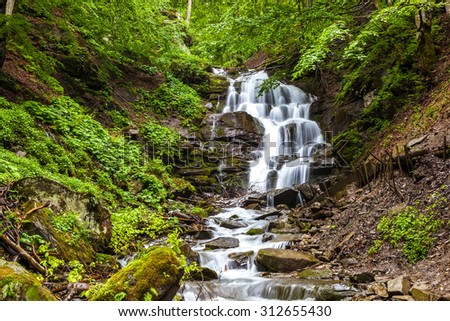 Mountain forest stream with a waterfall after a rain.