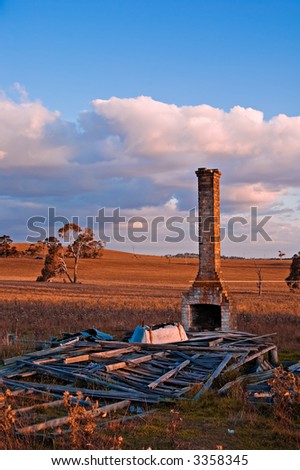 all that is left of this old farmhouse is a chimney, a pile of wood and an upturned bath
