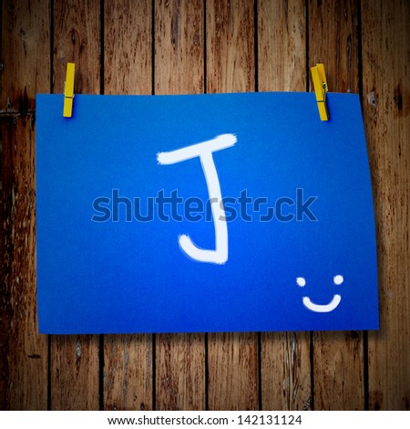 note paper and clothes peg on a wooden background with alphabet