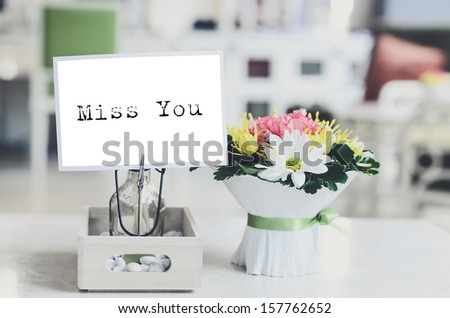 Postcard with message miss you and fresh flowers on table