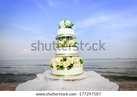 White and roses wedding cake by the beach