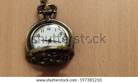 Vintage pocket watch on chain on wooden background