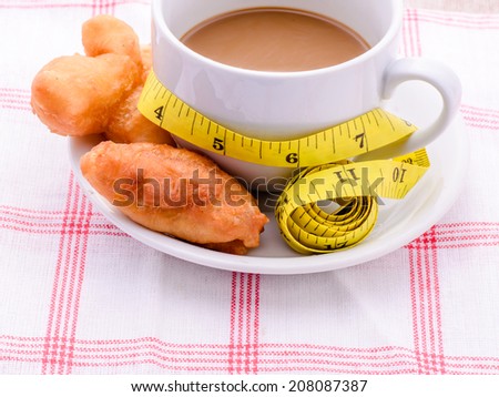 Deep fried dough stick, coffee and Measure tape,junk food concept