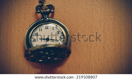 Vintage pocket watch on chain on wooden background