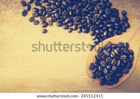 Coffee beans on a wooden ladle with wooden background, photo filter effect.