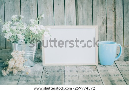 Vintage style White flowers stainless pot and blue pastel tea cup on wooden background, still life