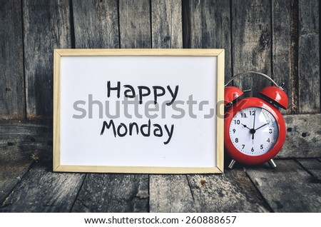 Happy Monday messae on white board and red retro clock  by wooden background.