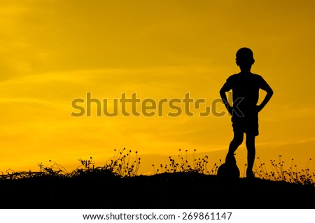 Silhouette of boy playing ball with sun set.