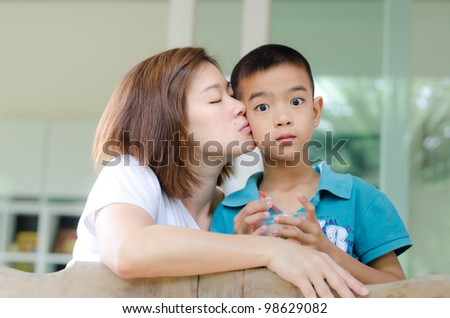 Mother kiss her son in front of the house