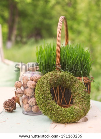 Handmade wheatgrass and moss wreath decor on a wooden table with nuts in a glass. Natural background